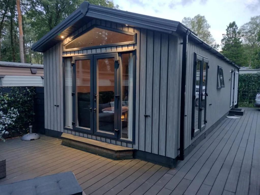 Buitenzijde van Chalet in Hoenderloo tussen de bomen op de Veluwe